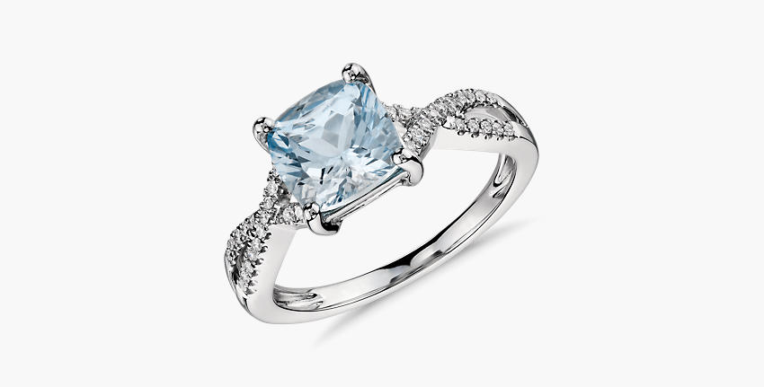 Un anillo de compromiso con aguamarina de talla cojín engarzada en oro blanco con pavé de diamantes de diseño torcido.