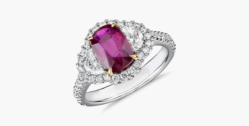 Un anillo de compromiso con rubí de talla cojín realzado por un halo y diamantes en forma de media luna