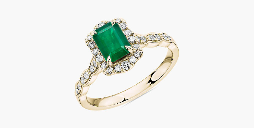 An emerald engagement ring ornamented by diamonds and gold filigree