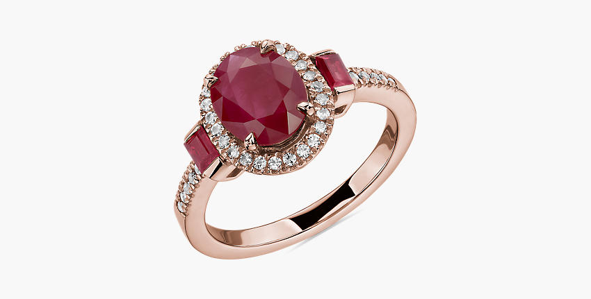 Un rubí ovalada realzado por gemas de talla baguette en un anillo de oro rosado.