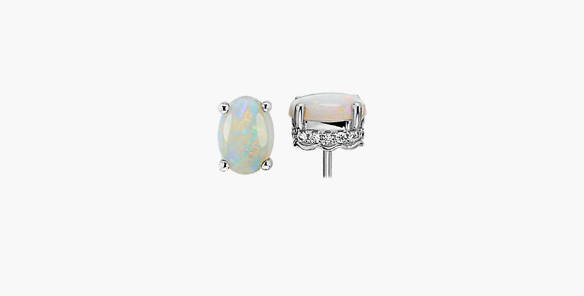 A pair of October birthstone stud earrings of smooth opal stones accented with lateral diamond detail in white gold