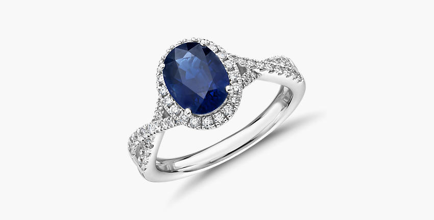 Un anillo de compromiso con zafiro azul en un engarce de diseño torcido de oro blanco con diamantes incrustados