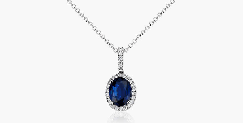 A blue oval sapphire gemstone and diamond pendant