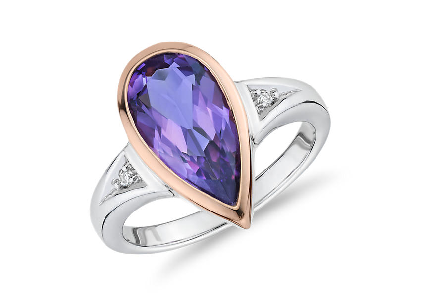 A pear shaped amethyst engagement ring that's bezel-set in two-toned rose and while gold and accented by round diamonds nestled in the band.