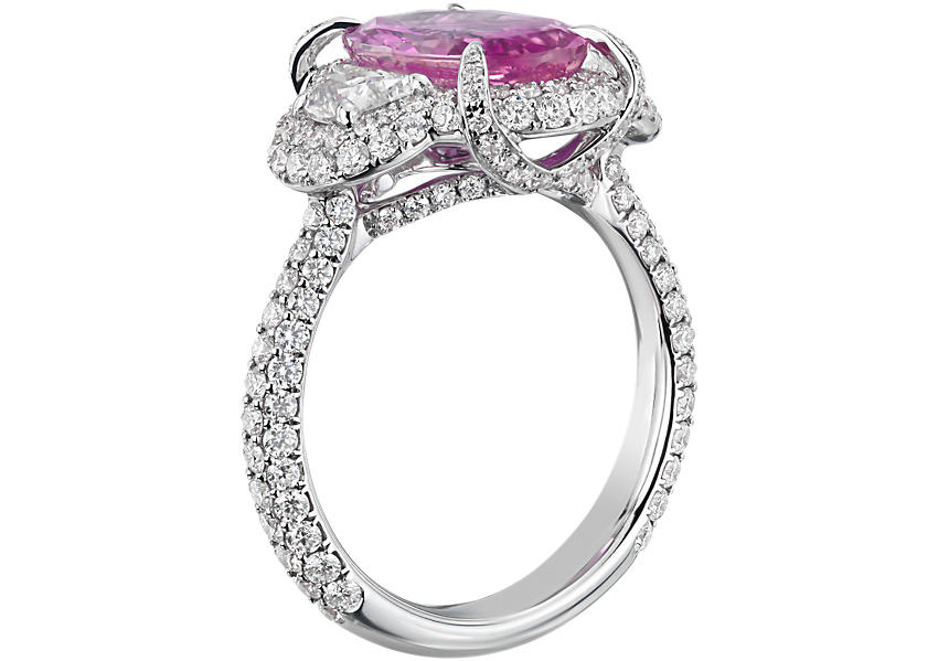 Vista lateral de un anillo de compromiso con zafiro rosado con pavé de diamantes, engarce en punta, halo, puente y alianza de oro blanco.