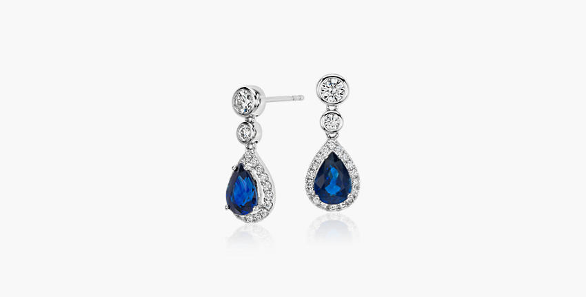 Blue pear shaped sapphire gemstones featured in a pair of dangly diamond earrings