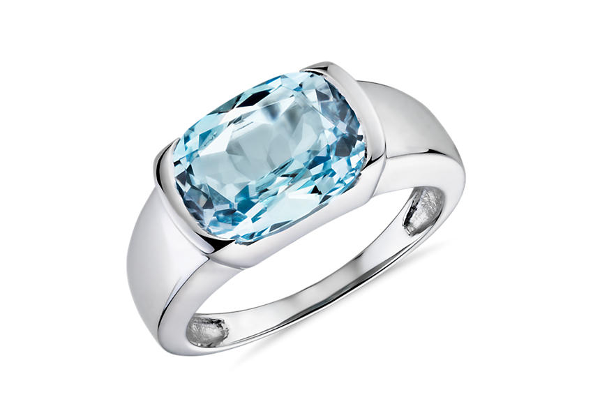 Un engarce semibiselado para un anillo de compromiso con topacio azul ovalado en oro blanco.