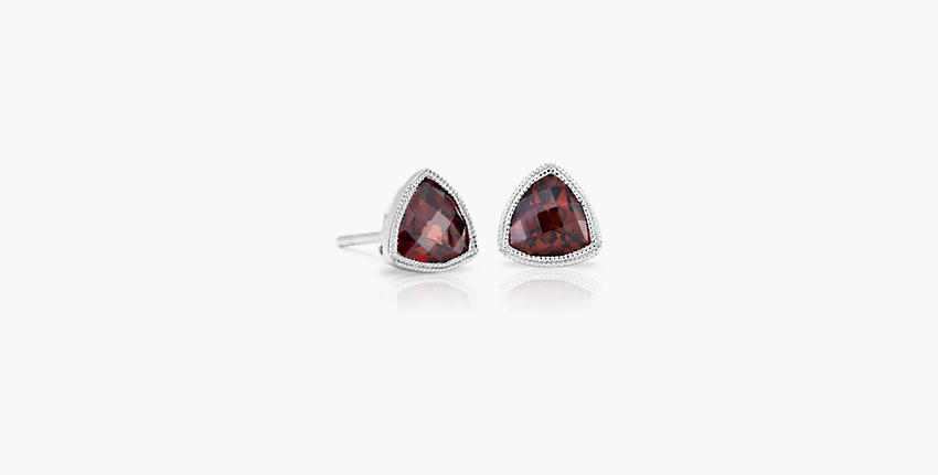 A pair of January birthstone earrings featuring bezel-set, trillion-cut garnets embellished with milgrain halos