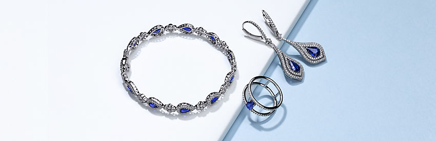 A bracelet, ring, and pair of earrings featuring sapphires surrounded by pavé-set diamonds.