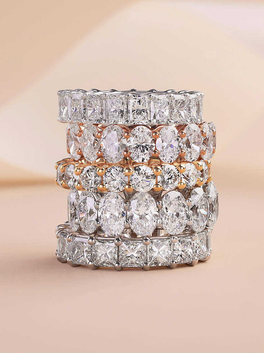 五枚永恒戒指叠戴，镶嵌不同切割形状的钻石，镶入白金和黄金中
