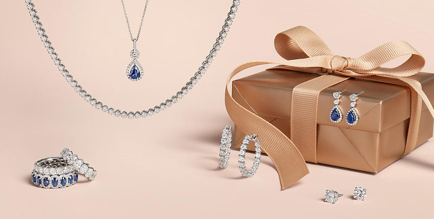 位於金色禮物盒上的鑽石與藍寶石首飾