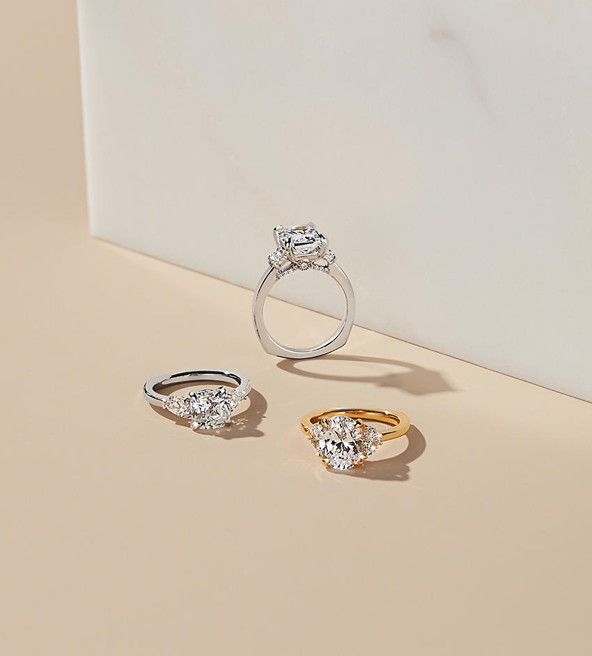 3 engagement rings on a tan background