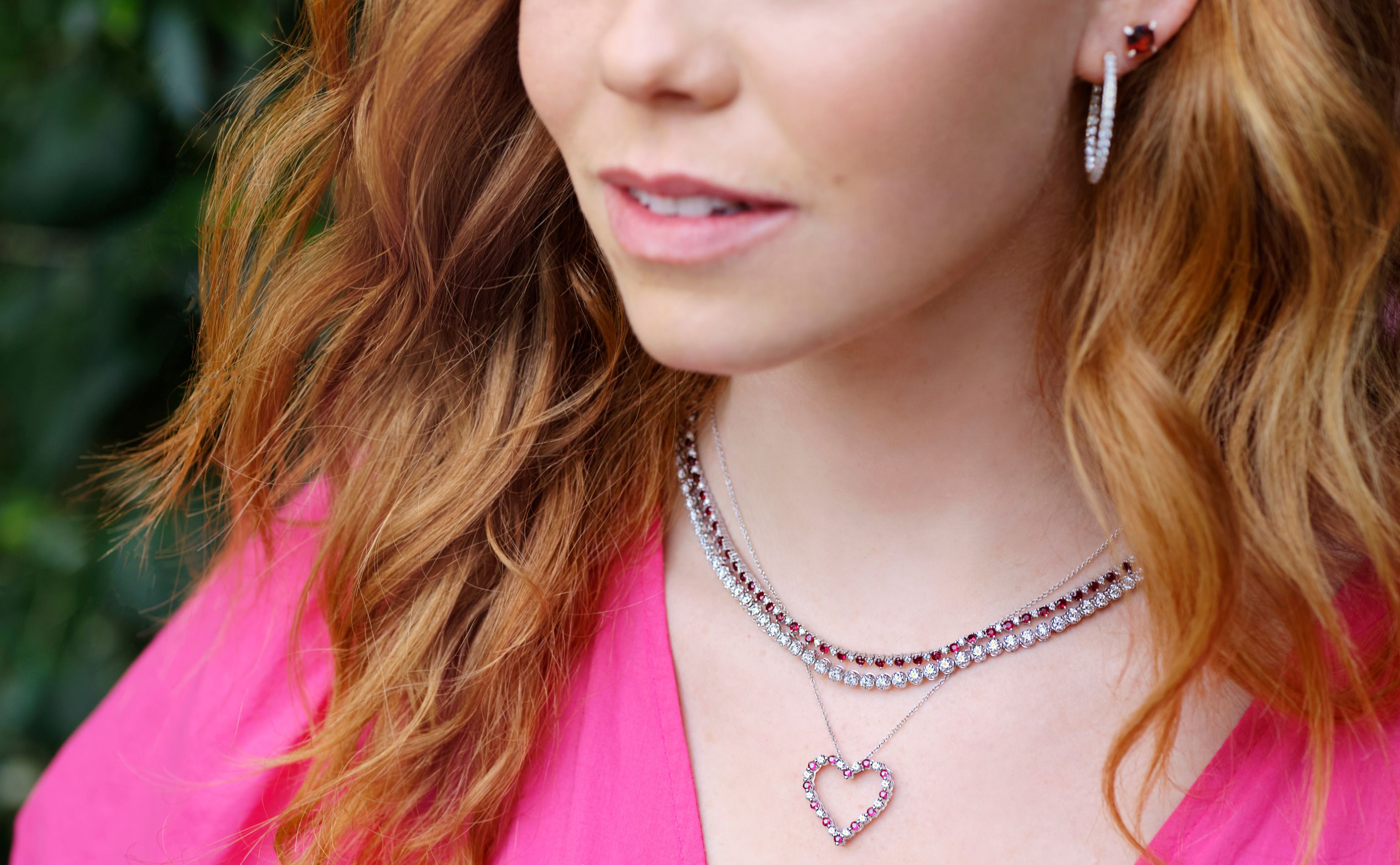 Woman with two eternity necklaces, a heart pendant, and diamond hoop earrings