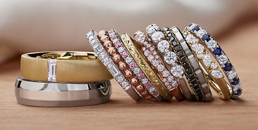 12 anillos de bodas de diversos diamantes, metales y diseños sobre una superficie color beige