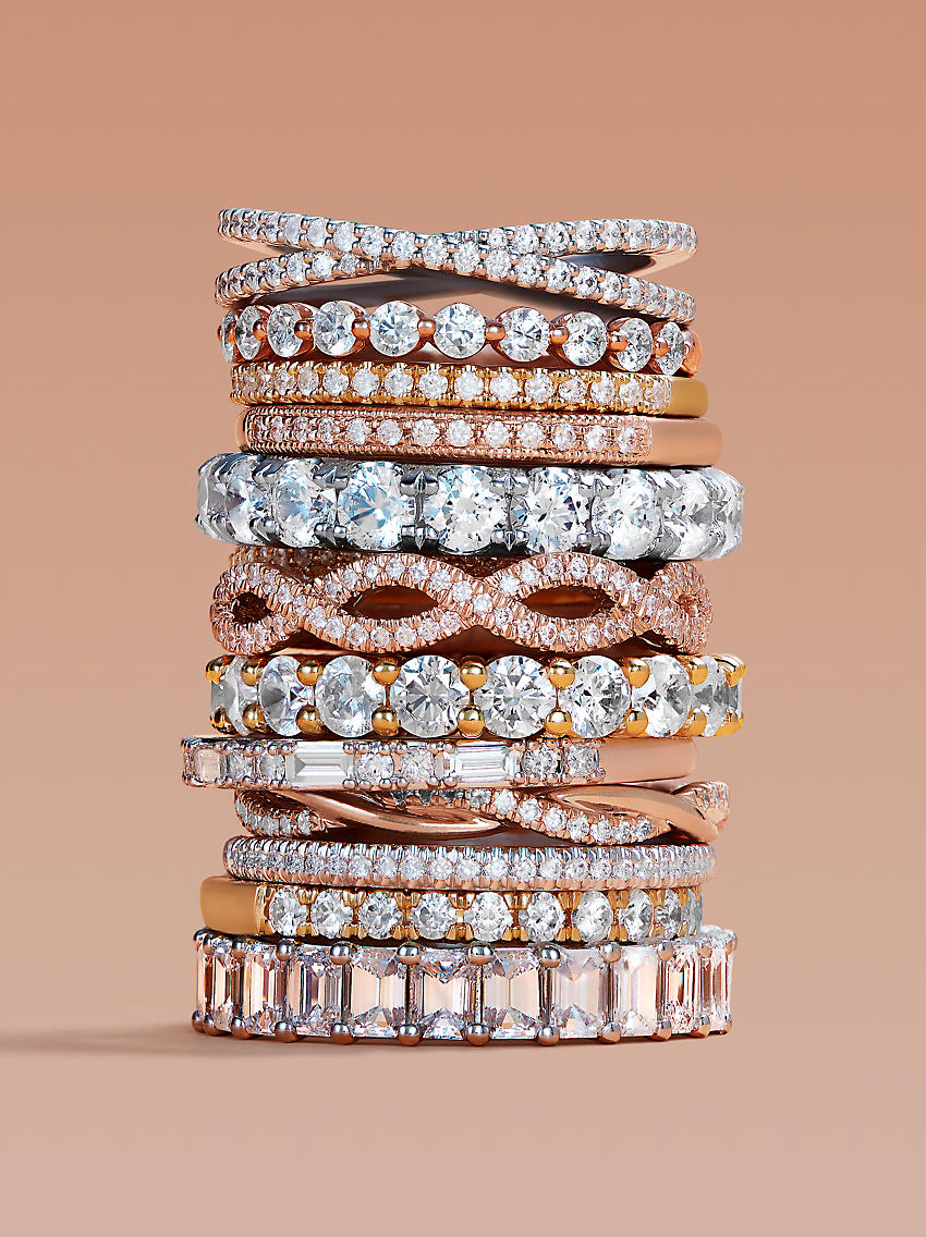 A large stack of diamond wedding rings in an array of different styles
