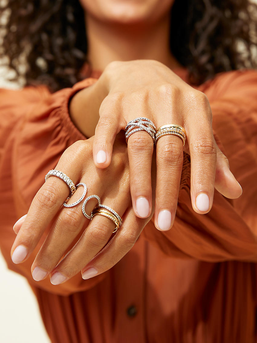 Una mujer usando una combinación de anillos de diamantes y metales preciosos