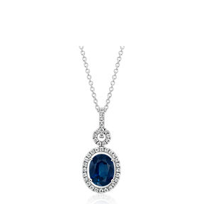 A vintage oval-shaped sapphire gemstone pendant necklace accented by a halo of round diamonds.