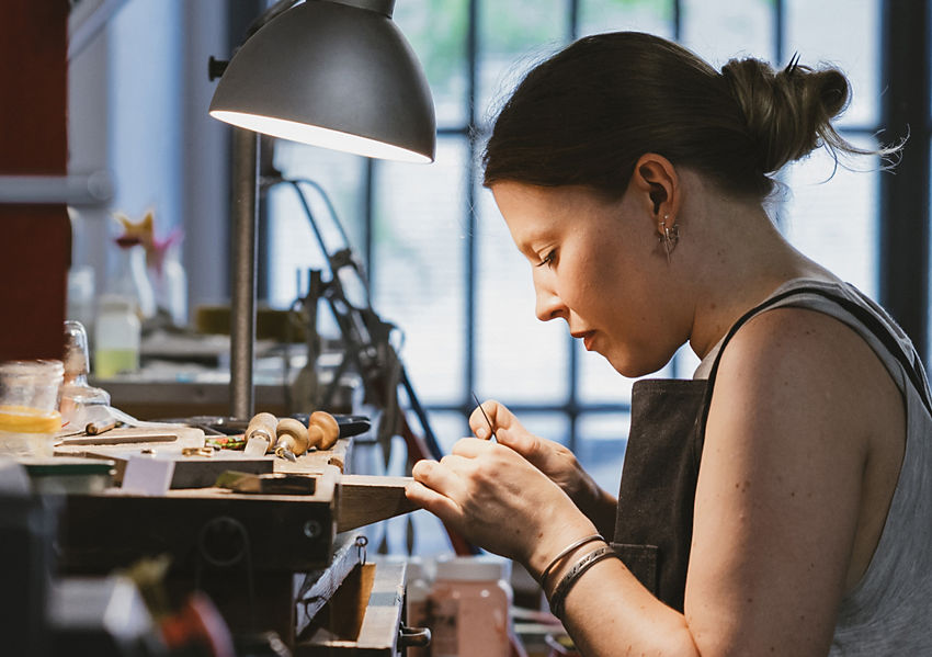 An artisan at a jeweler’s bench working on a custom diamond engagement ring