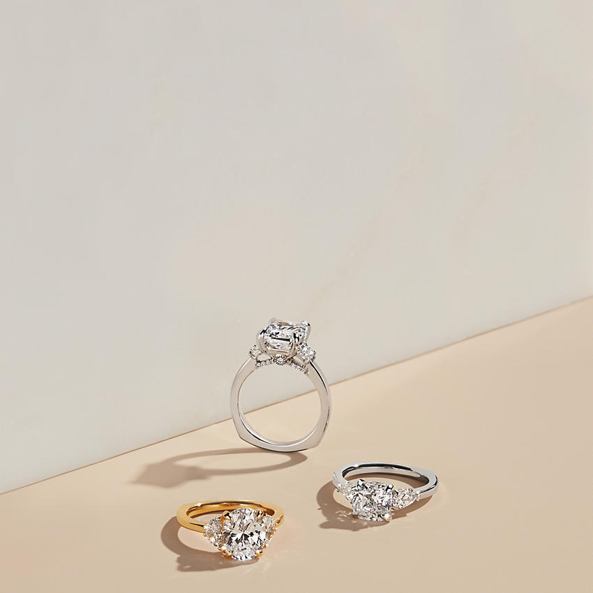 Three 3-stone engagement rings in various metals