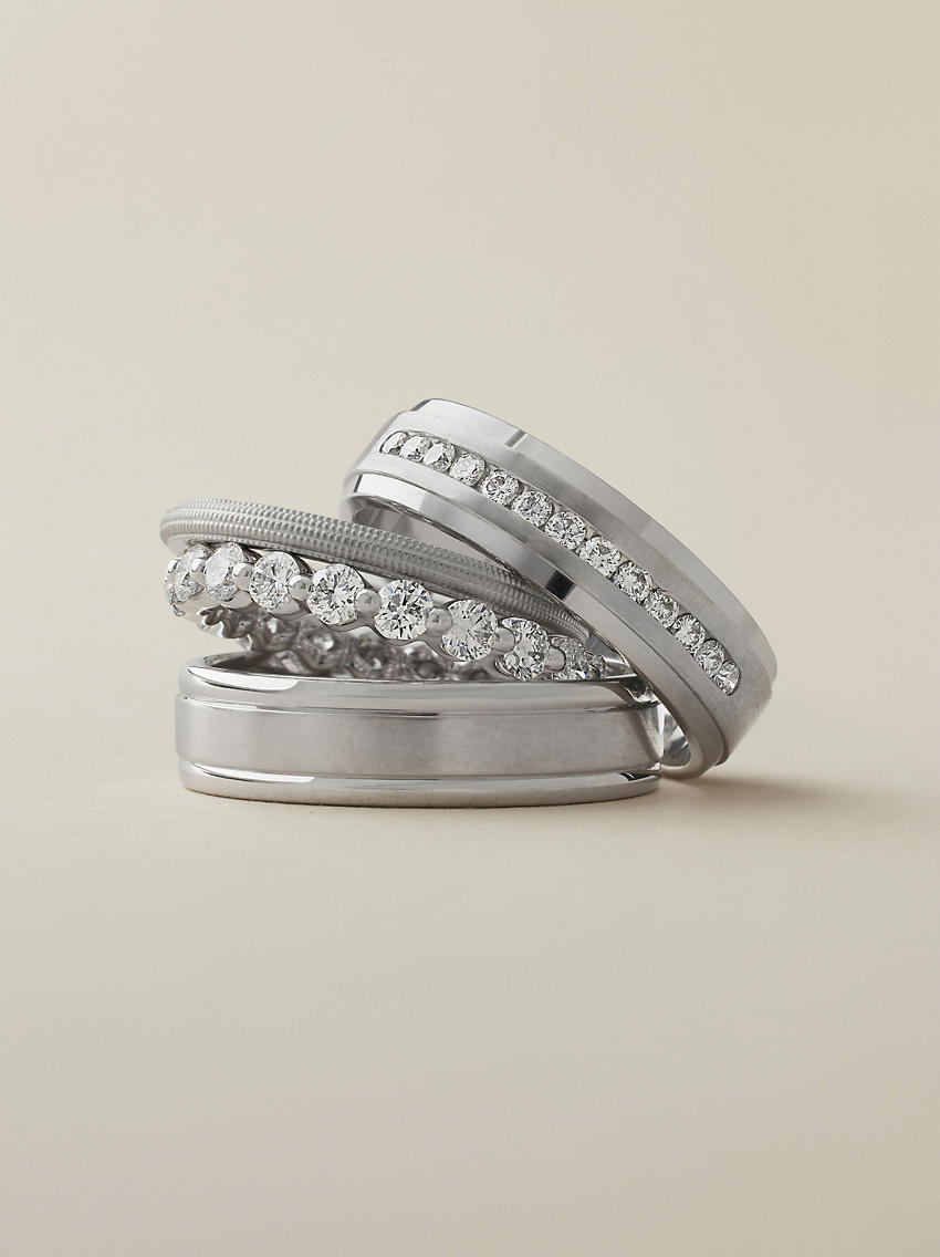 A channel set diamond platinum wedding ring stacked on top of two platinum wedding rings and a diamond eternity ring