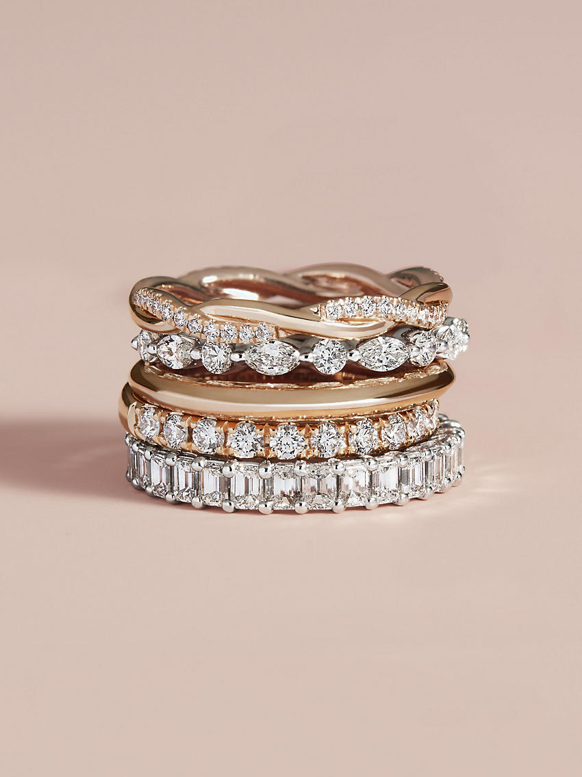 A stack of rose gold wedding rings and diamond eternity wedding rings.