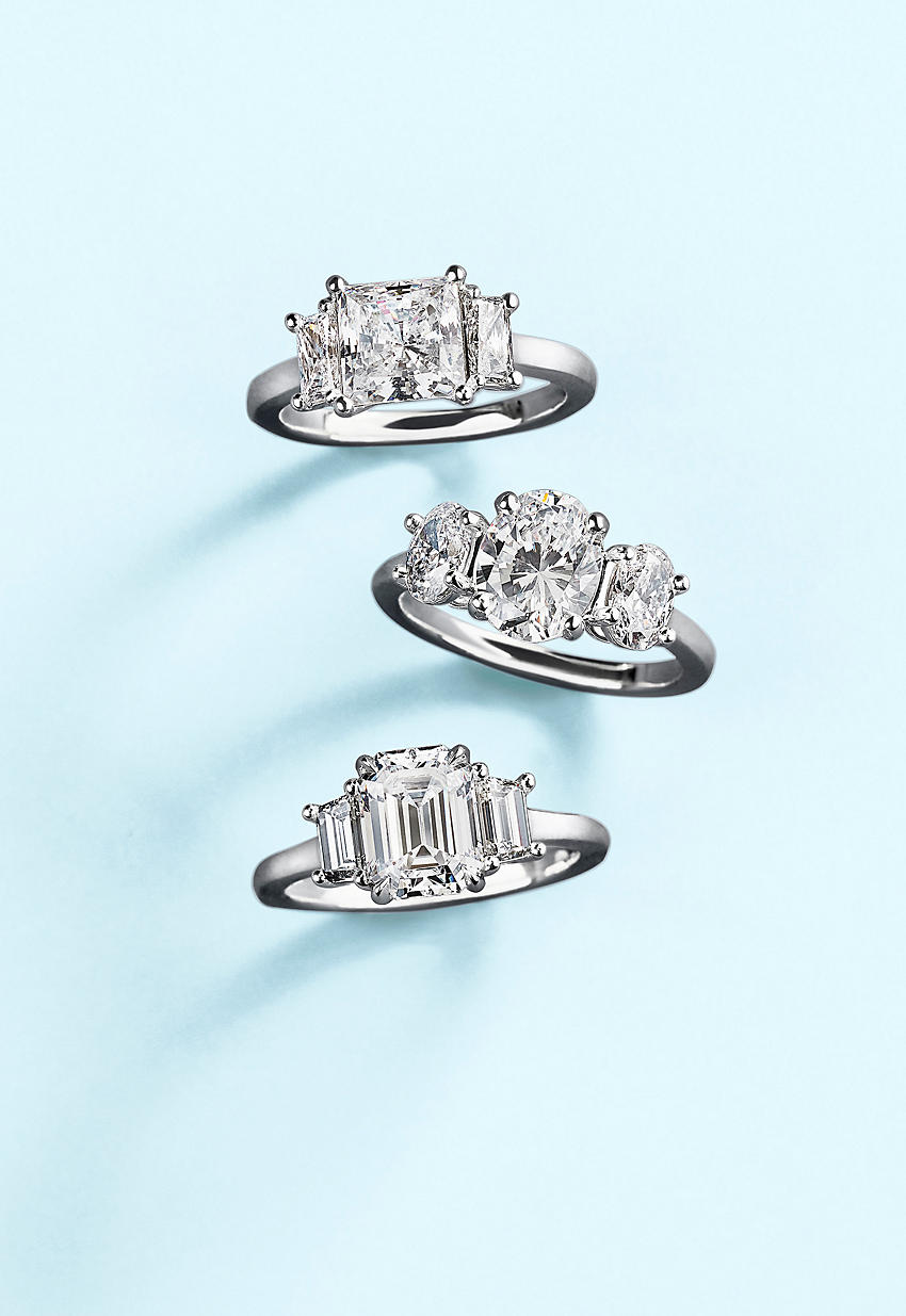 Un trío de anillos de compromiso de tres piedras brillantes